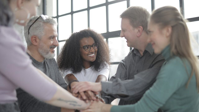 A support group is standing together with their hands connecting.